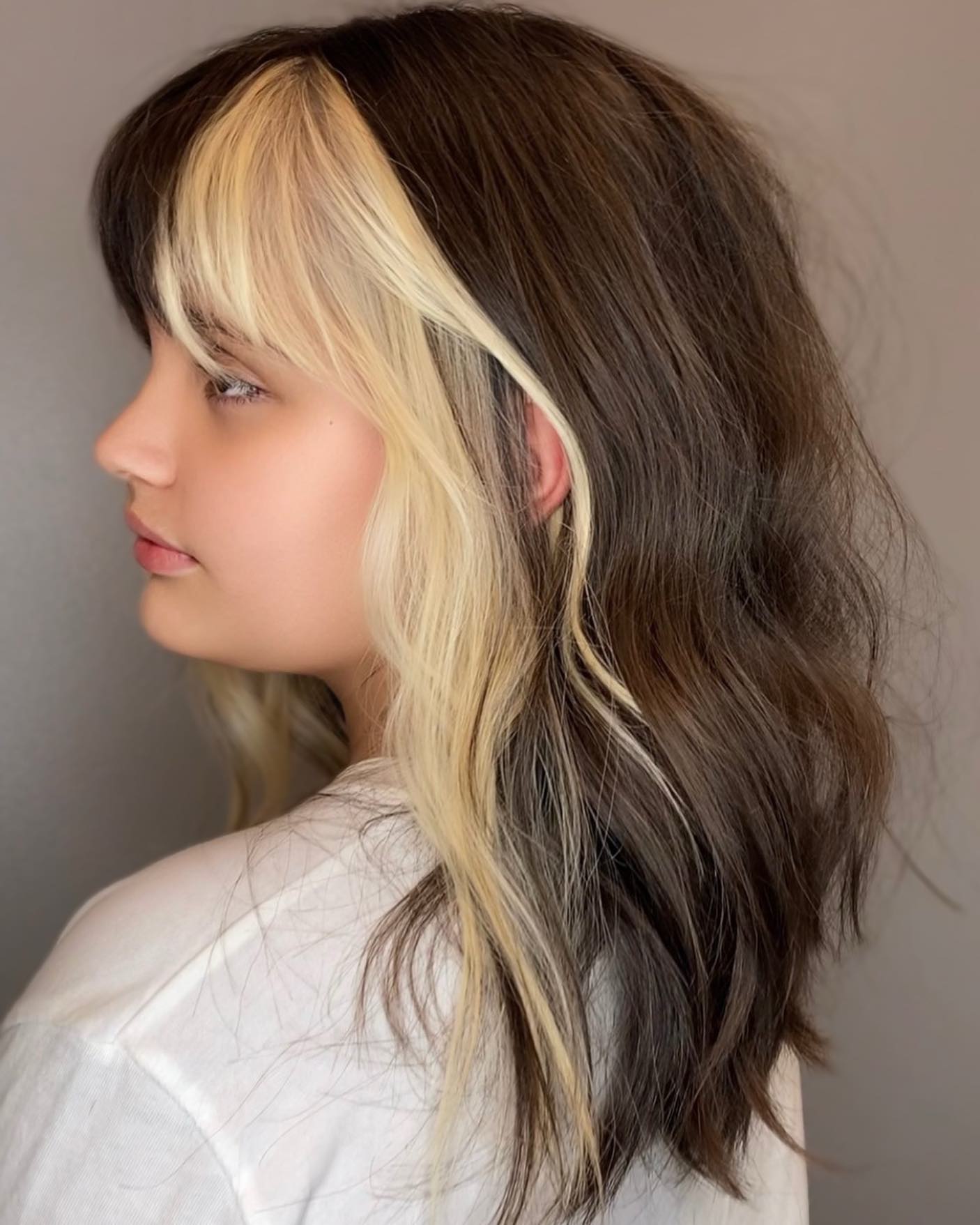 Profile of a client with dark hair and a bright blonde underneath panel revealed at the front, by CRIS HAIR in Malden