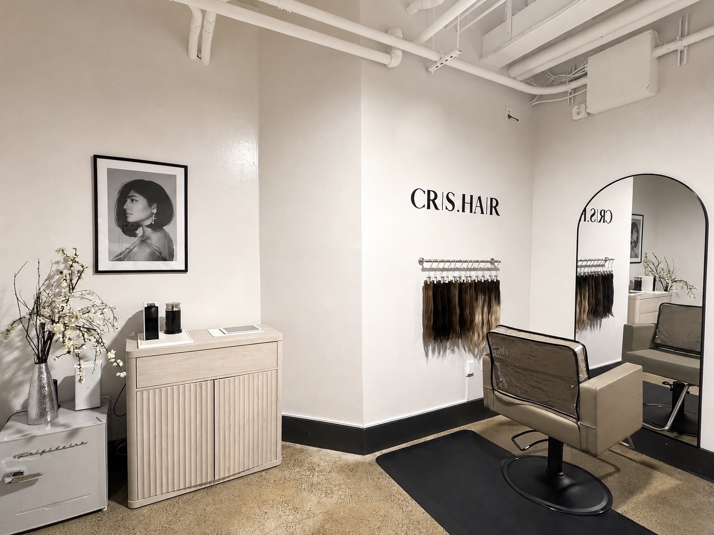 Wide view of the CRIS HAIR private studio with the styling chair, arched mirror, CRIS.HAIR logo, extensions, and cabinetry